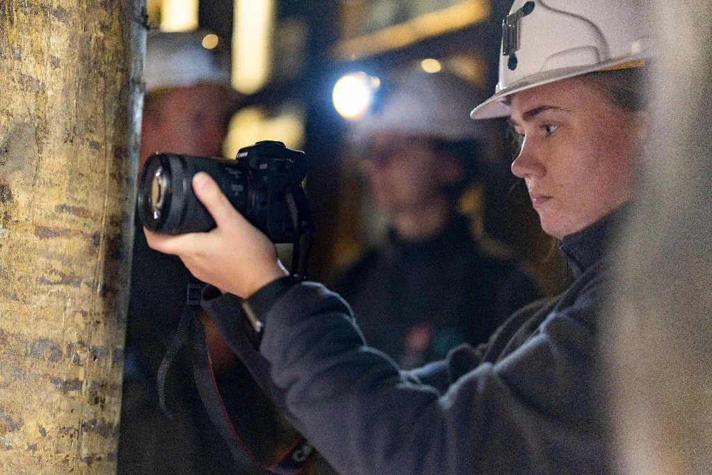 Osoba w kasku fotografuje wnętrze wyrobiska